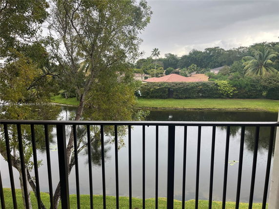 View of trees, a lake, and residential houses from a balcony.