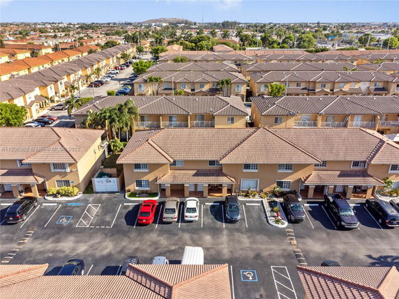 Aerial view of a residential area with multiple identical two-story houses and parking spaces.
