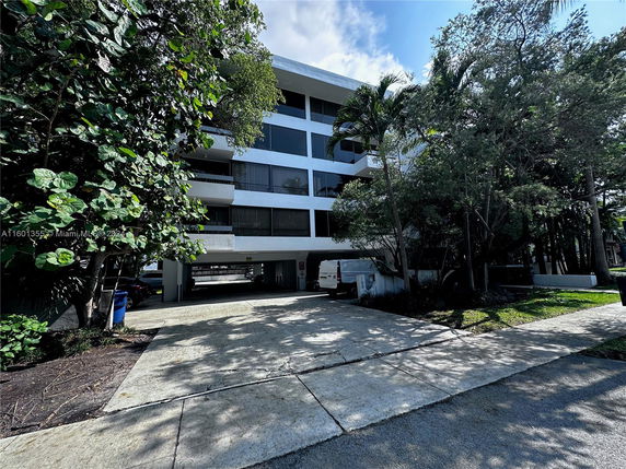 Front view of a multi-story building with a covered parking area.