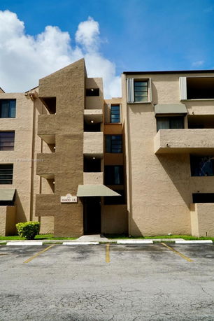 Front view of a multi-story building with balconies and a covered entrance.