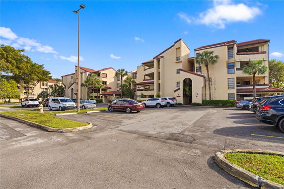 Front view of a multi-story residential building with adjacent parking area.