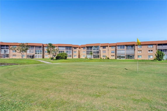 Front view of a three-story building with a large lawn area in front.