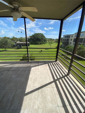View from a balcony overlooking a grassy area with trees and buildings in the distance.