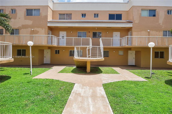Front view of a multi-story residential building with balconies and a central staircase.