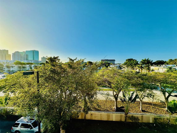 View of a cityscape with trees, buildings, and a vehicle visible.