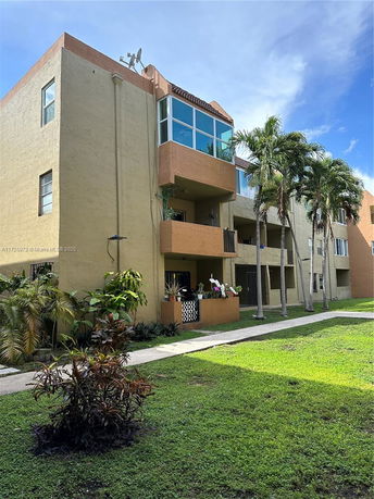 Front view of a multi-story residential building with balconies and satellite dish on the roof.