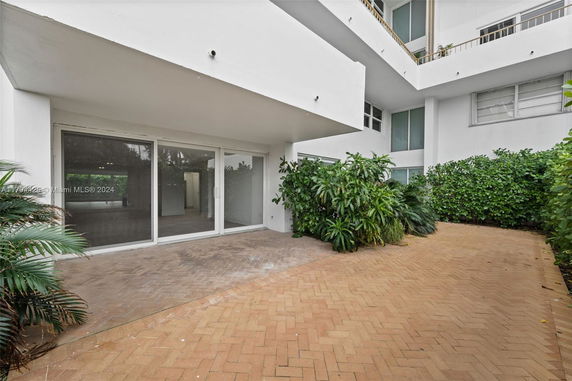 Front view of a building with large glass sliding doors and surrounding greenery.