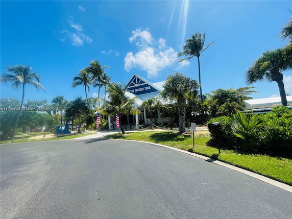Front view of a building with a triangular roof and palm trees nearby.