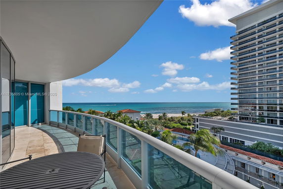 Coastal view from a balcony with ocean and neighboring buildings.