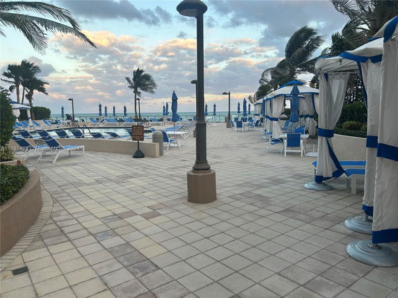 Outdoor area with a swimming pool and lounge chairs near the ocean.
