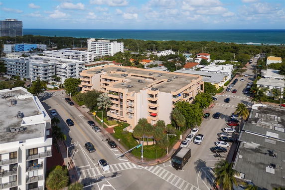 Aerial view of a neighborhood with apartment buildings and streets, ocean in the background.