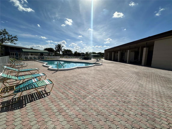 Outdoor swimming pool with lounge chairs and adjacent building.