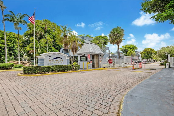Entrance view of Beach Club complex, featuring a gated security booth and signage.