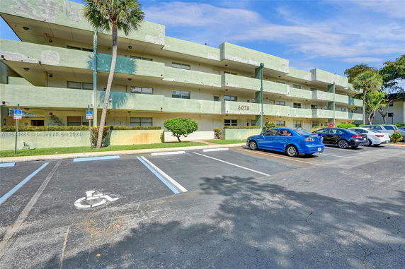 Front view of a three-story residential building with a parking area in front.