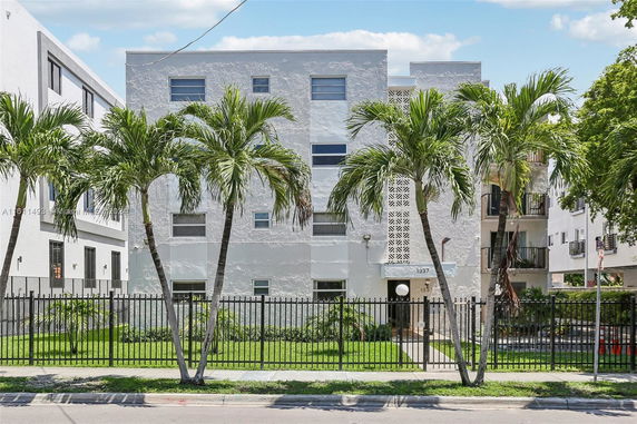 Front view of a multi-story residential building with a gated entrance.
