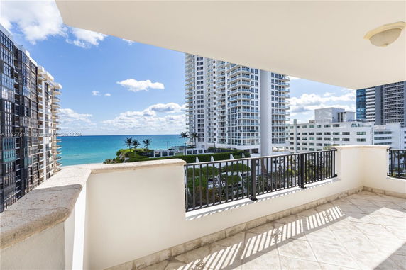 Panoramic view from a balcony showing high-rise buildings and the ocean.