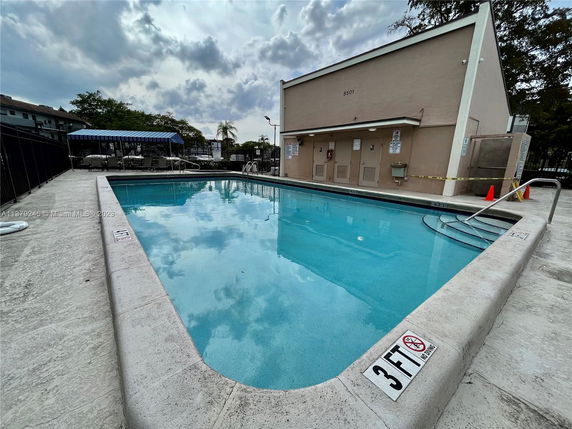 Outdoor swimming pool with adjacent building and seating area.