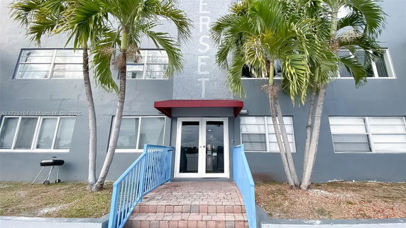 Front view of a building with a glass entrance and palm trees.