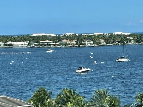 View of the ocean with several boats and distant houses along the shoreline.