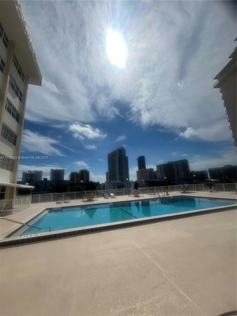Outdoor swimming pool on a rooftop with tall buildings in the background.