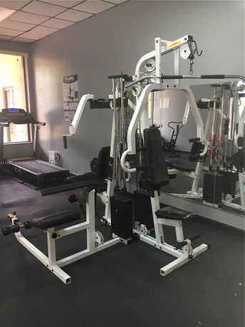 Indoor gym area with exercise equipment including a treadmill and a weight machine.