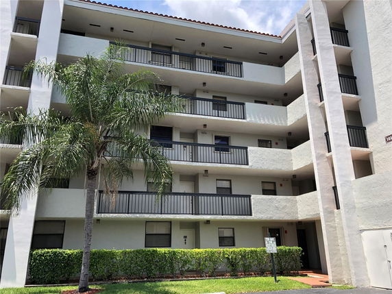 Front view of a multi-story apartment building with balconies and railings.