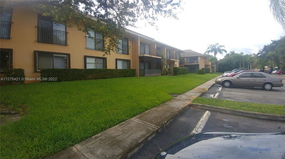 Front view of a two-story residential building with adjacent parking lot.