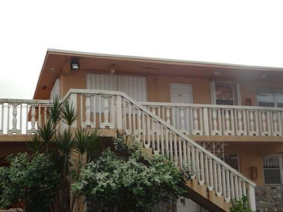 Front view of a two-story building with exterior stairs and a balcony railing.