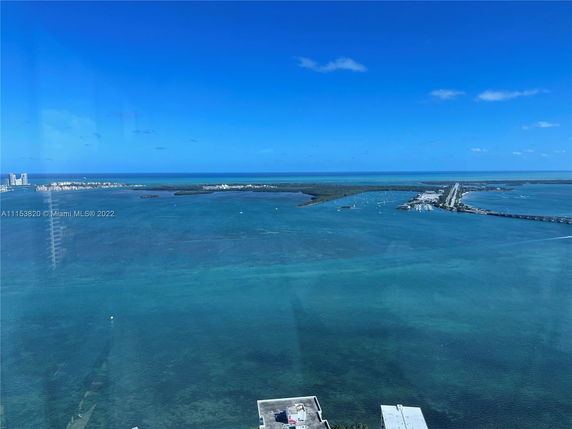 Wide panoramic view of a bay with distant islands and a bridge.