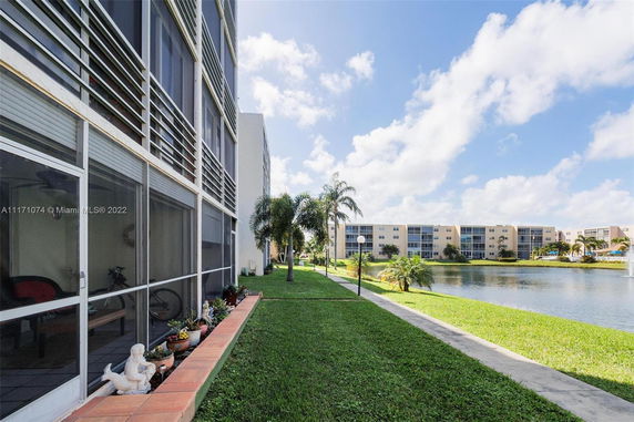 Exterior view of multi-story buildings near a water body with a landscaped area.