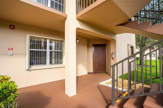 Front view of an apartment entrance with stairs and a brown door.