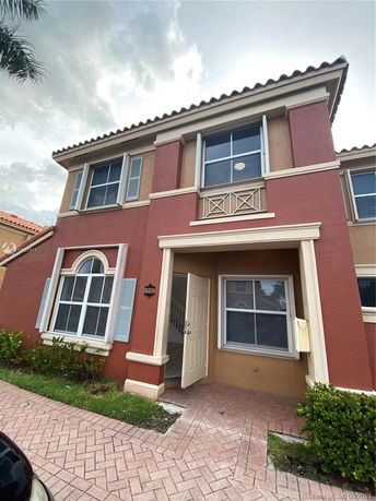 Front view of a two-story house with a brick facade and multiple windows.
