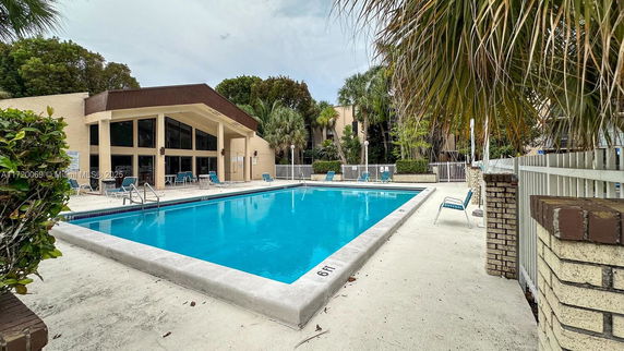 Outdoor swimming pool area adjacent to a building with large windows.