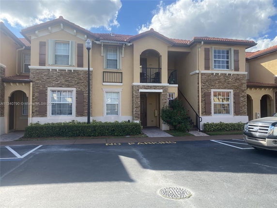 Front view of a two-story residential building with a light brown facade and decorative stone elements.