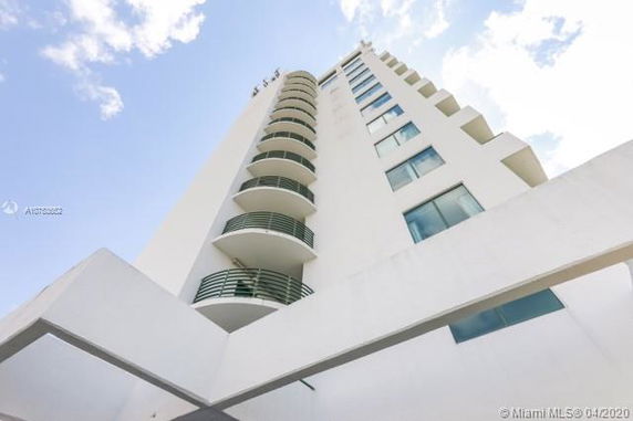 View of a tall building with multiple balconies and windows against a blue sky.