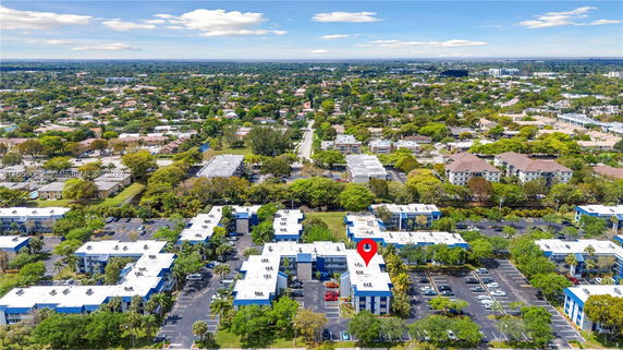 Aerial view of a residential area with multiple low-rise buildings, parking lots, and green spaces.