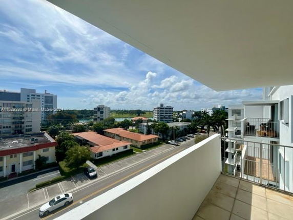 View of surrounding area from a balcony with several buildings and a road below.