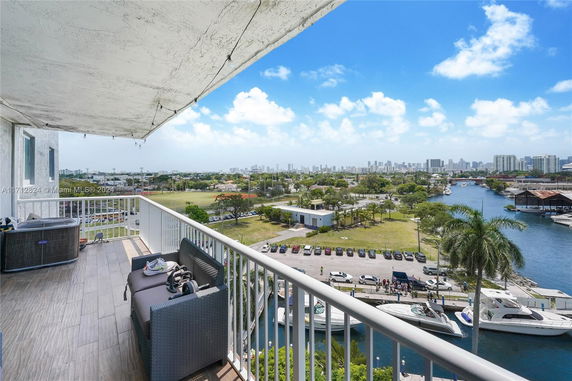 Wide angle view from a balcony overlooking a waterway, with boats and a distant city skyline.