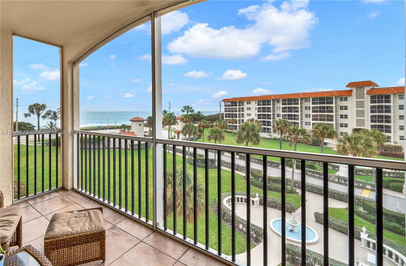 View from a balcony overlooking a landscaped area and a distant ocean.