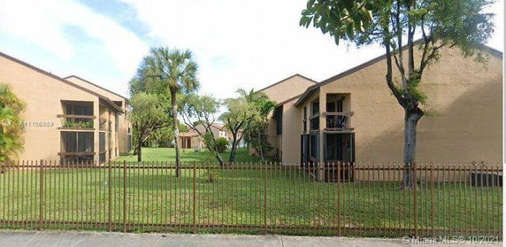 Front view of a two-story residential building with balconies and trees.