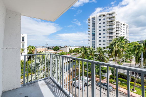 Panoramic view from a balcony overlooking city buildings and palm trees.