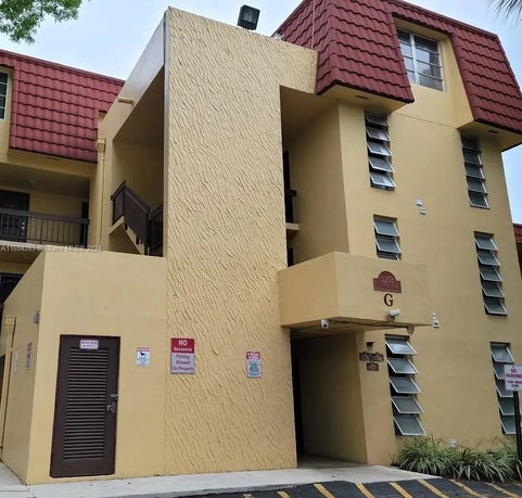 Front view of a multi-story building with red roof tiles and yellow walls.