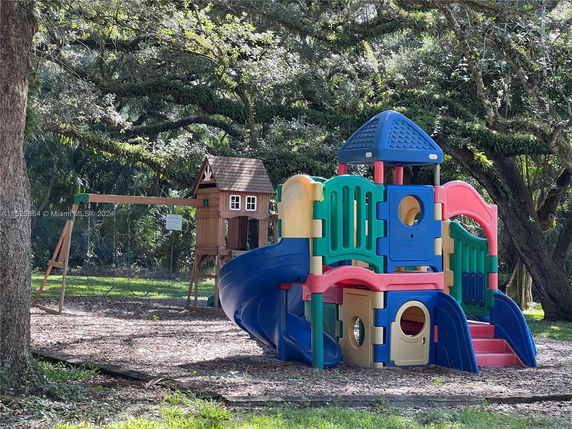 Playground area with colorful slide structure and a small wooden playhouse.
