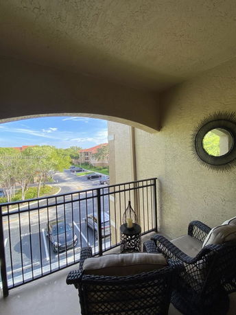 Balcony view overlooking a parking area and neighboring buildings.