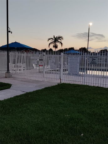 Outdoor swimming pool area with a fence and umbrellas.