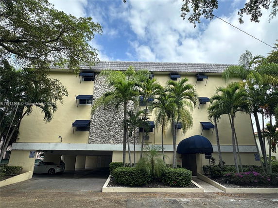 Front view of a multi-story building with stone facade and parking area.