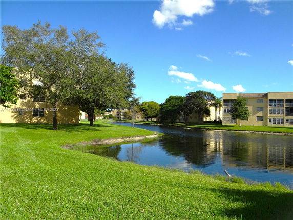 View of apartment buildings with a pond and trees in the surroundings.