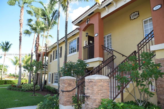 Front view of a two-story building with stairs and decorative columns.