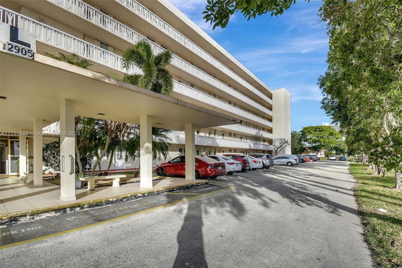 Front view of a multi-story building with multiple balconies and a covered entrance area.