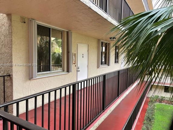Exterior corridor of a multi-story building with red flooring and beige walls.